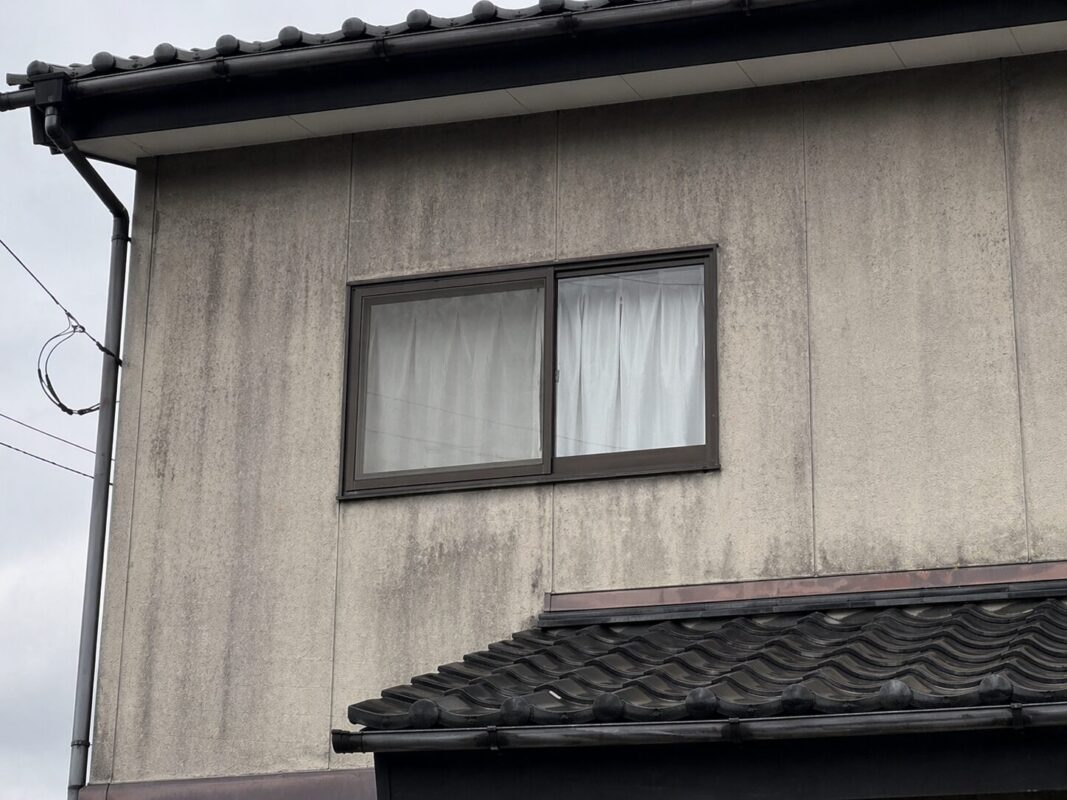モルタル外壁の色褪せ・変色の実例｜全体的にくすんで雨筋の黒ずみも広がっている状態
