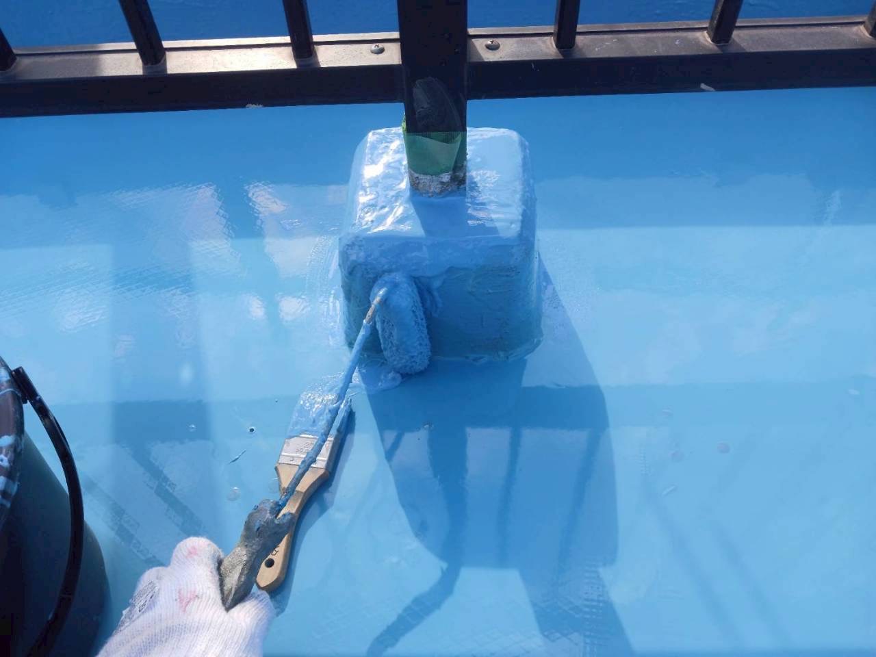 屋上防水工事でローラーを使って防水材を施工している現場の様子