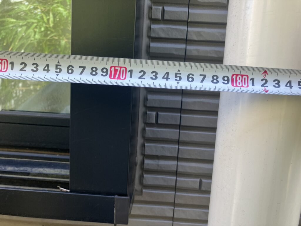 サッシ廻りコーキングの横幅をメジャーで測り、寸法を確認しているアップ写真